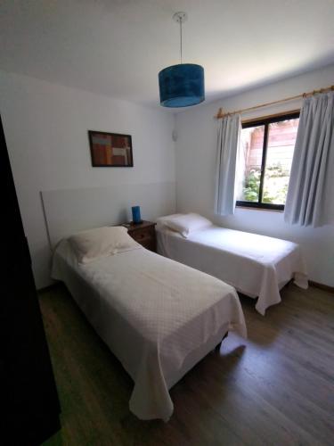 two beds in a room with a window at Mar de Estrellas Apart Hotel in La Paloma