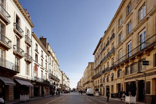 a street with buildings and people walking down a street at Maison d'hôtes Bordeaux Centre Le Patio de l'Intendance in Bordeaux