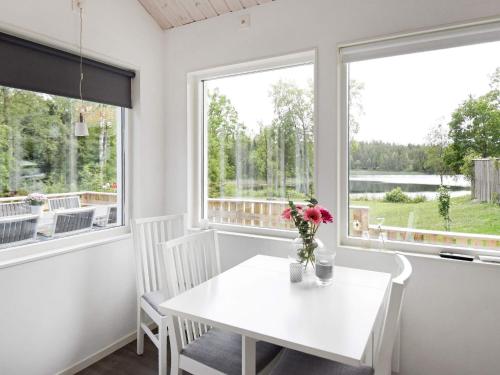 a white dining room with a table and two windows at 4 person holiday home in Brålanda in Brålanda