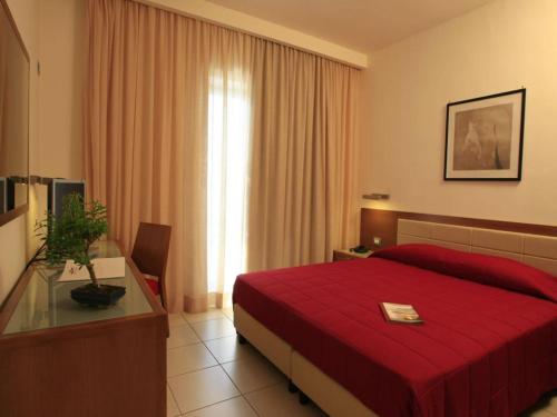 una camera d'albergo con letto rosso e finestra di La Costiera Hotel a Marina di Varcaturo