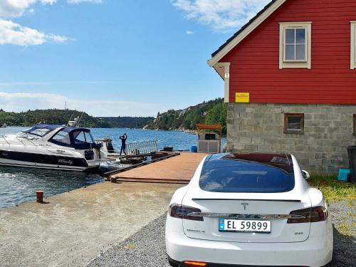 a white car parked next to a house and a boat at 4 person holiday home in Urangsv g in Ervik