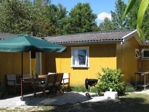 a yellow house with a table and an umbrella at 6 person holiday home in Dannemare in Dannemare