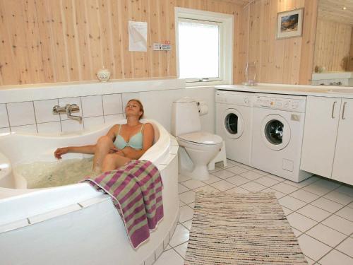 uma mulher sentada numa banheira na casa de banho em 8 person holiday home in L kken em Lokken