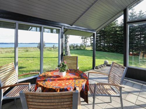 a table and chairs on a patio with a view of the ocean at 4 person holiday home in H jslev in Højslev