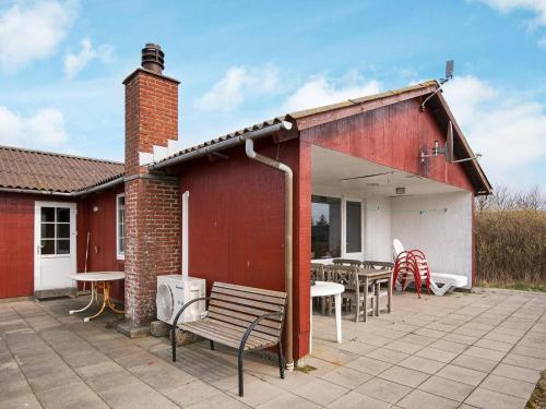 - un bâtiment rouge avec une terrasse dotée d'une table et de chaises dans l'établissement 6 person holiday home in R m, à Lakolk