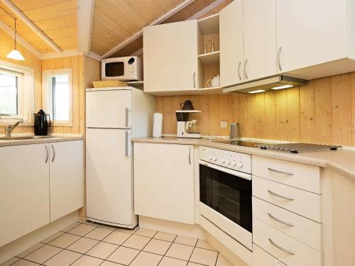 a kitchen with white appliances and wooden walls at 7 person holiday home in Asn s in Asnæs