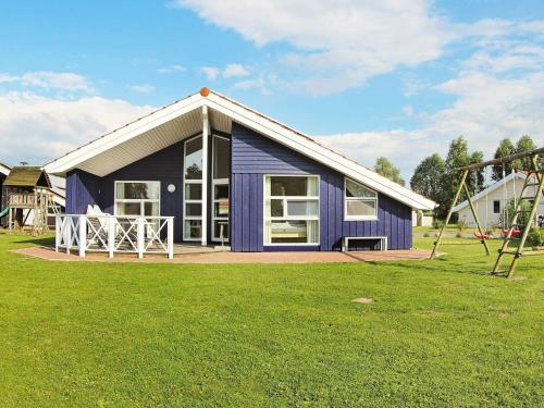 ein blaues Haus mit einer Veranda und einem Spielplatz in der Unterkunft 12 person holiday home in Otterndorf in Otterndorf