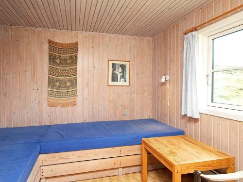 1 dormitorio con cama azul y mesa de madera en Two-Bedroom Holiday home in Ringkøbing 9, en Søndervig