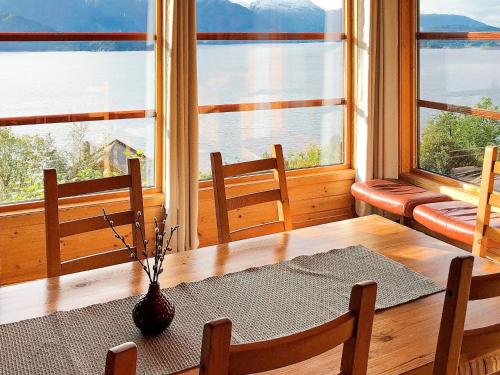 a dining room with a table and chairs and windows at 8 person holiday home in Norheimsund-By Traum in Norheimsund