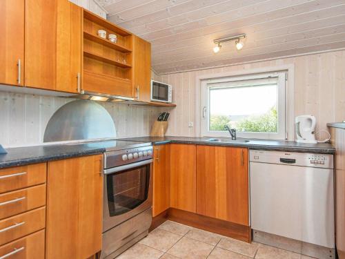cocina con armarios de madera, fregadero y ventana en 6 person holiday home in Hemmet, en Falen