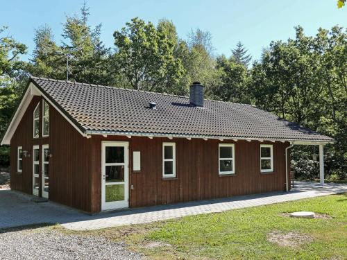 Oddeにある6 person holiday home in Hadsundの白い窓と木々が特徴の小さな茶色の家