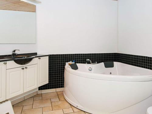 y baño con bañera blanca y lavamanos. en 6 person holiday home in Bl vand, en Blåvand
