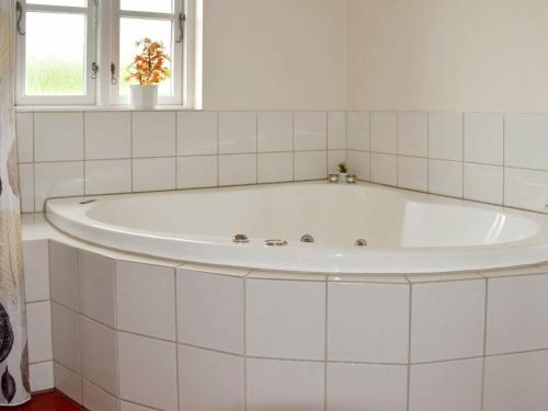 baño con bañera blanca y ventana en Holiday Home Horns Bjerge IV, en Blåvand