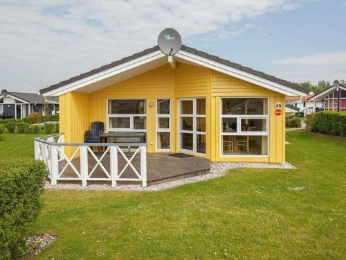 a yellow house with a deck in a yard at 6 person holiday home in GROEMITZ in Grömitz