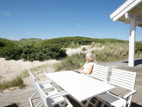 a woman sitting at a table on the beach at 10 person holiday home in L kken in Grønhøj