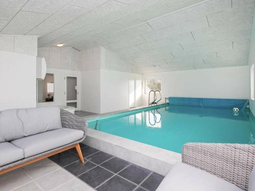a large swimming pool in a room with a couch at 12 person holiday home in Vejers Strand in Vejers Strand