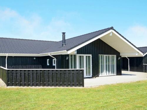 a black house with a fence in front of it at 8 person holiday home in Tarm in Hemmet
