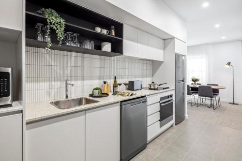 a kitchen with white cabinets and a sink at Quest Wangaratta in Wangaratta