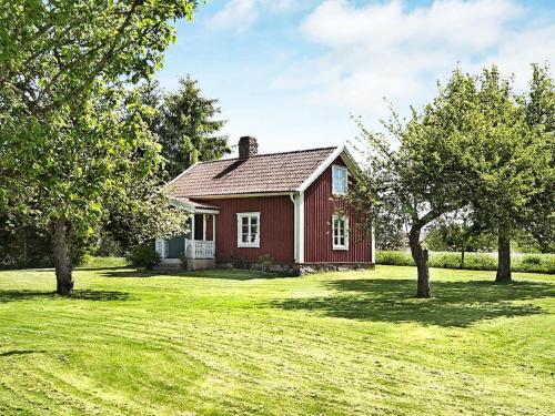 uma pequena casa vermelha num campo com árvores em 4 person holiday home in ANKARSRUM em Hult