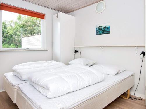 a white bedroom with a large bed with white sheets at Four-Bedroom Holiday home in Bogense 3 in Skåstrup