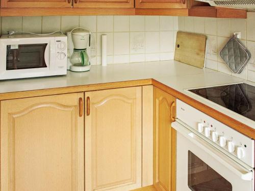 a kitchen with wooden cabinets and a white microwave at 8 person holiday home in VÅGLAND-By Traum in Vågland