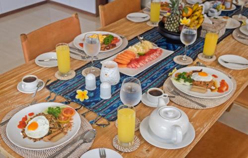 ein Tisch mit Tellern voller Essen und Gläsern mit Orangensaft in der Unterkunft Kubu GWK Resort in Jimbaran