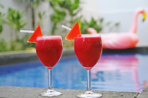 Drei Cocktails mit Wassermelonen darin sitzen neben einem Pool in der Unterkunft Kubu GWK Resort in Jimbaran
