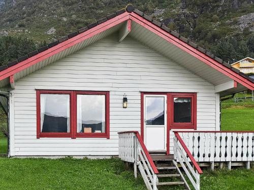 uma casa branca com janelas vermelhas e um alpendre em 7 person holiday home in Selje em Selje