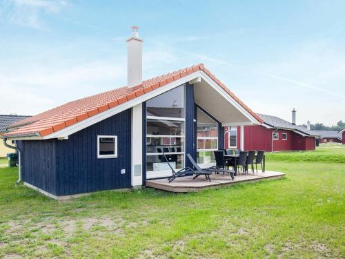 ein blaues Haus mit einer Terrasse und Stühlen auf einem Feld in der Unterkunft 8 person holiday home in Gro enbrode in Großenbrode