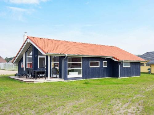 una casa azul con techo naranja en un campo en 8 person holiday home in Gro enbrode, en Großenbrode