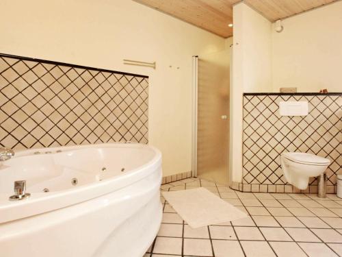 a white bathroom with a tub and a toilet at 9 person holiday home in J gerspris in Jægerspris