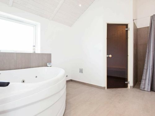 a large white bath tub in a bathroom with a window at Holiday Home Hansavej in Marielyst