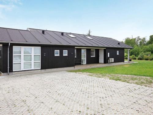 een zwart huis met een oprit ervoor bij 8 person holiday home in Brovst in Brovst