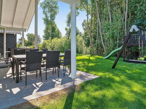 a patio with a table and chairs and a playground at 18 person holiday home in Hasselberg in Kappeln
