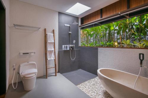 a bathroom with a tub and a toilet and a sink at Zenubud in Ubud
