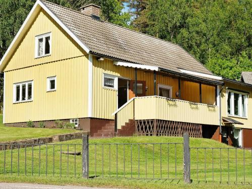 żółty dom z płotem przed nim w obiekcie 6 person holiday home in ULLARED w mieście Ullared