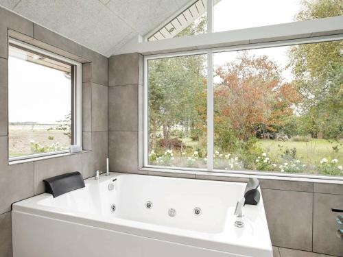 a large white bath tub in a bathroom with windows at Two-Bedroom Holiday home in Tomrefjord in Gørlev