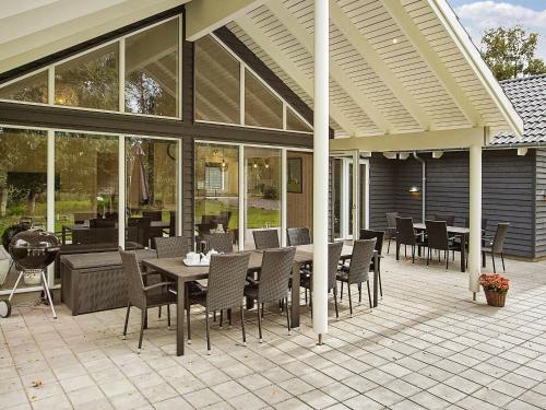 a patio with tables and chairs and a grill at 18 person holiday home in H jby in Højby