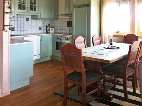 Tuvnes的住宿－Three-Bedroom Holiday home in Dyrvik，一间带桌椅的厨房和一间带白色橱柜的厨房