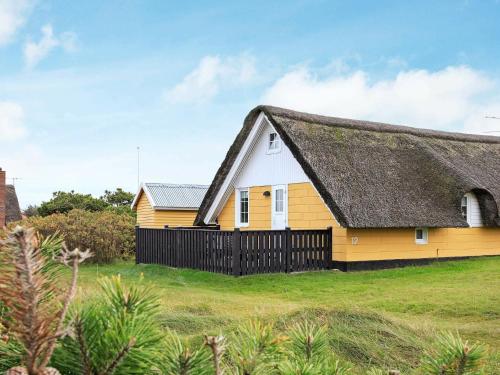 een geel en wit huis met een rieten dak bij 6 person holiday home in Ringk bing in Ringkøbing