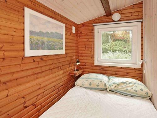 ホにあるThree-Bedroom Holiday home in Blåvand 77の木造キャビン内のベッド1台が備わるベッドルーム1室を利用します。