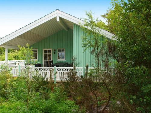 una casa verde con una valla blanca delante de ella en 8 person holiday home in Hemmet en Hemmet