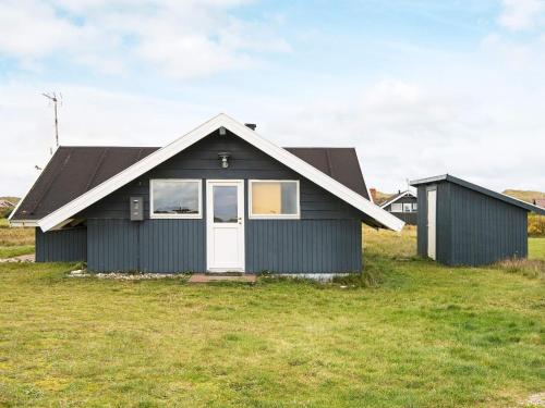 a black house with a white door in a field at 5 person holiday home in Harbo re in Harboør