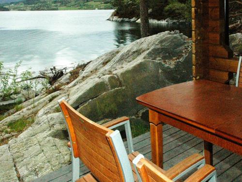a table and chairs on a porch with a view of the water at 5 person holiday home in VÅGLAND in Bårdset