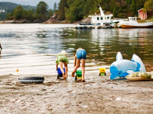 two children playing on a beach near the water at 5 person holiday home in VÅGLAND in Bårdset