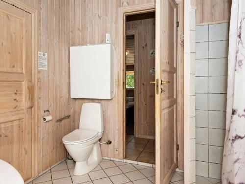 a bathroom with a toilet in a wooden wall at Holiday Home Trinnesvej in Bolilmark
