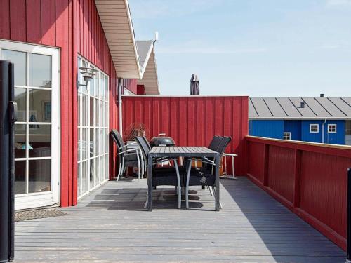 a patio with a table and chairs on a red building at 6 person holiday home in Hvide Sande in Hvide Sande