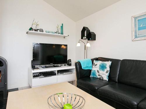 a living room with a black couch and a tv at 6 person holiday home in Hvide Sande in Hvide Sande