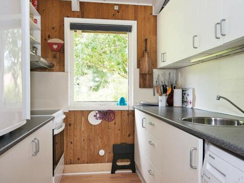 eine Küche mit weißen Schränken und einem Fenster in der Unterkunft 4 person holiday home in lb k in Ålbæk