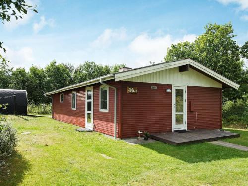 eine kleine rote Hütte mit einer Veranda im Hof in der Unterkunft 4 person holiday home in lb k in Ålbæk